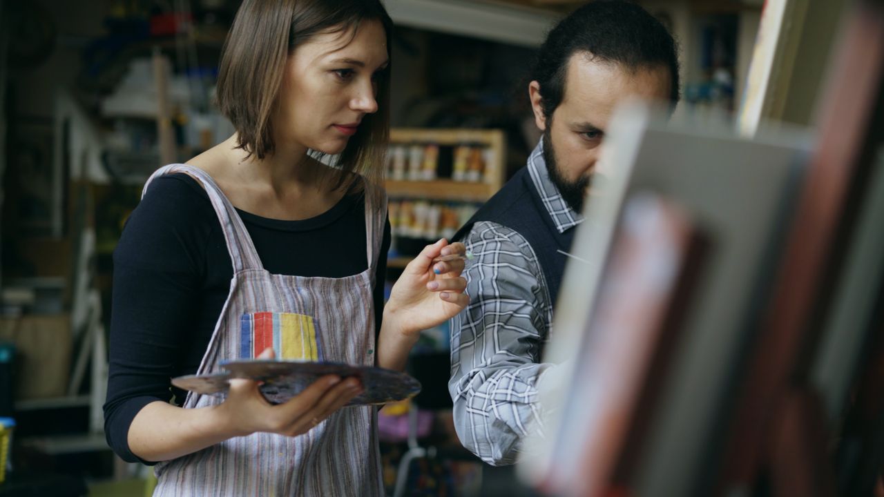 Two artists engaged in painting, focused on their creative process in a studio.